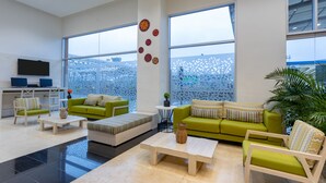 A modern living room with a green sofa, a wooden coffee table, and a TV mounted on the wall. - Mia Hotel Chocó By OxoHotel (Quibdó)
