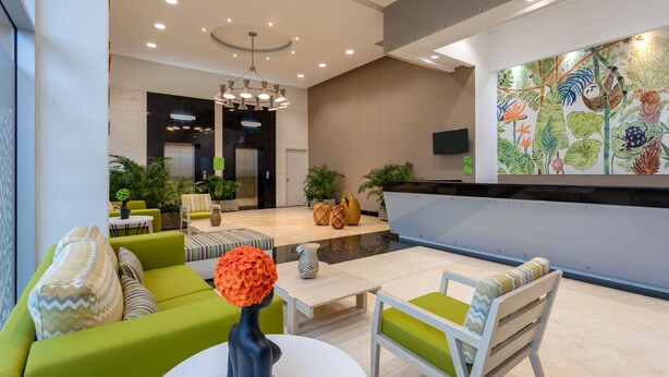 A modern lobby with a green sofa, white coffee table, and a colorful mural. - Mia Hotel Chocó By OxoHotel (Quibdó)
