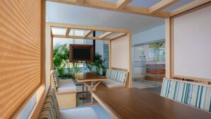 A modern meeting room with a wooden table, cushioned benches, a television, and a glass partition with a view of the outdoors. - Mia Hotel Chocó By OxoHotel (Quibdó)