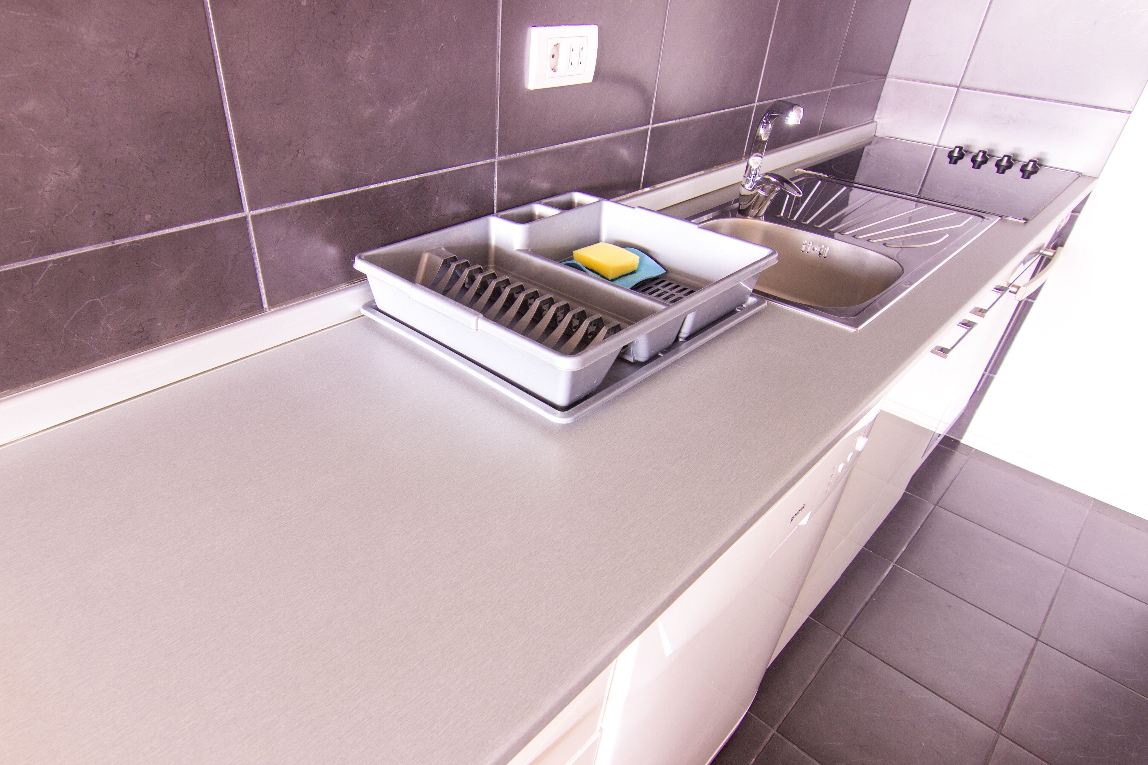 Een moderne keuken met een roestvrijstalen spoelbak, een afdruiprek en een inbouwoven.