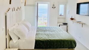 A bedroom with a bed, bedside table, and a TV mounted on the wall.