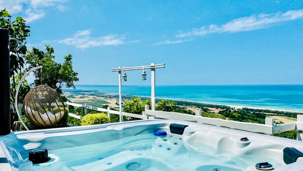 A hot tub with a view of the ocean and beach.