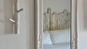 A bedroom with a large ornate mirror, a wooden headboard, and a wall-mounted light fixture.
