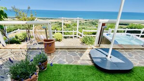 A patio with a view of the sea, a hot tub, and potted lavender plants.