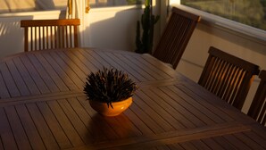 A wooden dining table with a potted plant, a hanging planter, and a view of the landscape through large windows.