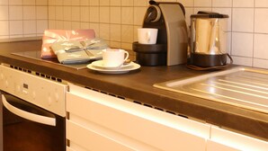 A kitchen with white cabinets, a coffee maker, and a kettle on the counter. - Eine schöne Wohnung in Kupferdreh (Essen)