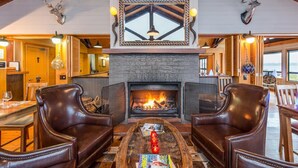 Un intérieur chaleureux et accueillant, avec une cheminée en pierre, des fauteuils en cuir et un coin repas.