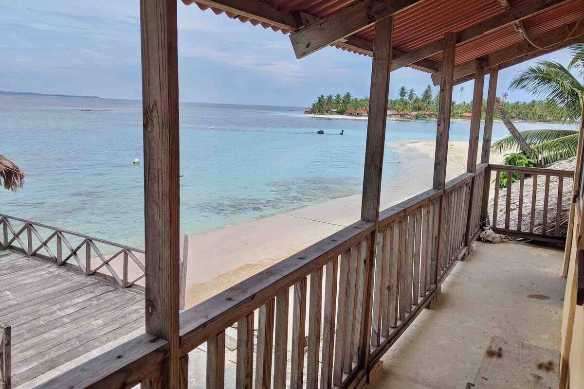 A wooden deck with a view of a beach and ocean.
