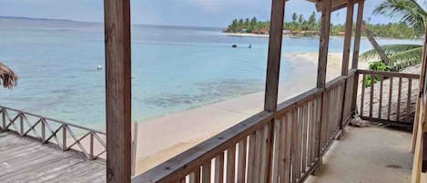 A wooden deck with a view of a beach and ocean.
