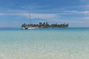 A clear view of a small island with a boat anchored nearby.