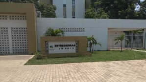 A paved entrance with a sign for 'ENTRESIERRAS' and a gated area with palm trees. - Apartamento conjunto Entre Sierras (Valledupar)
