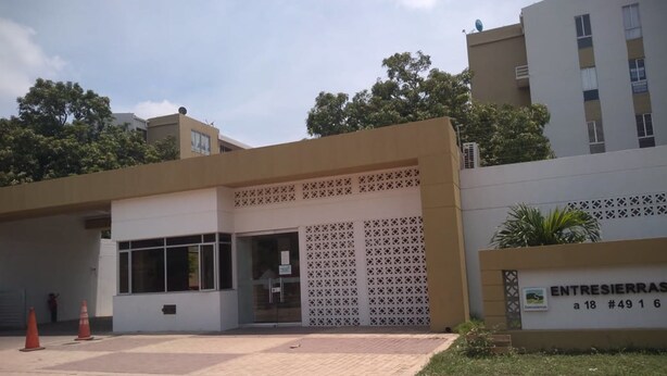 A building with a modern architectural style, featuring a flat roof and a large entrance with a decorative lattice. - Apartamento conjunto Entre Sierras (Valledupar)