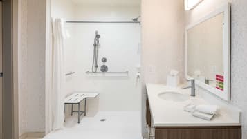Un baño moderno con ducha, lavamanos y espejo.