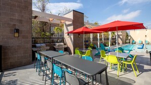 An outdoor patio with tables and chairs, a barbecue grill, and a swimming pool. - Home2 Suites by Hilton Houston IAH Airport Beltway 8 (Houston)