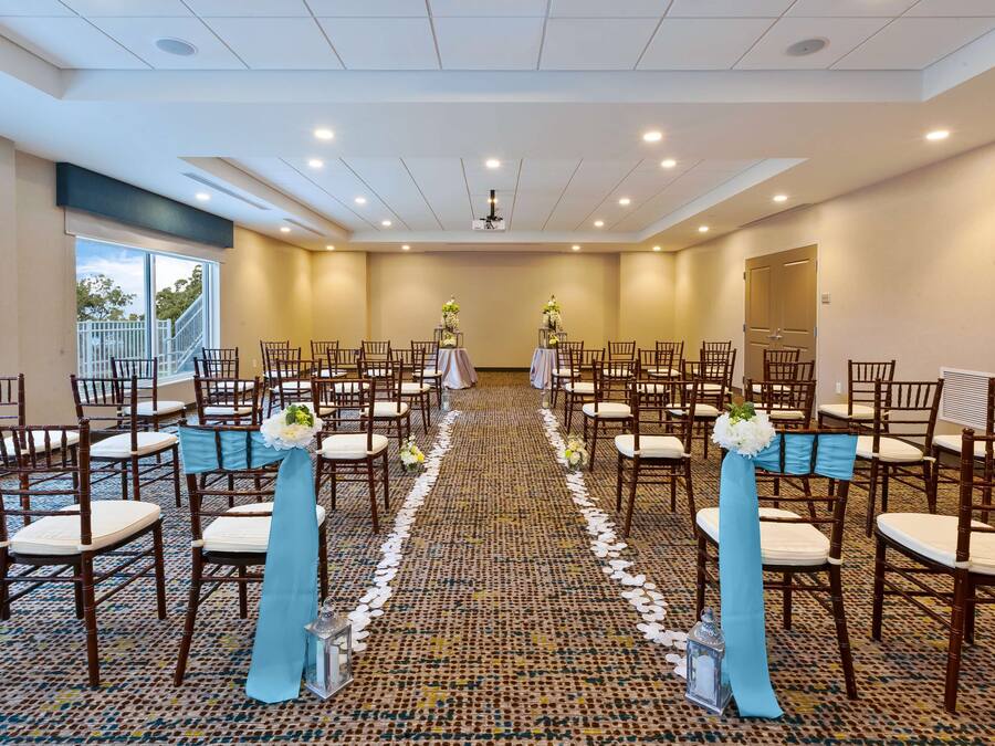 A conference room with rows of wooden chairs, a carpeted floor, and a central aisle.