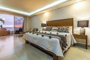 A spacious bedroom with a large bed, two bedside tables, a nightstand, and a view of the ocean. - The Paramar Beachfront Boutique Hotel - Downtown Malecon (Puerto Vallarta)
