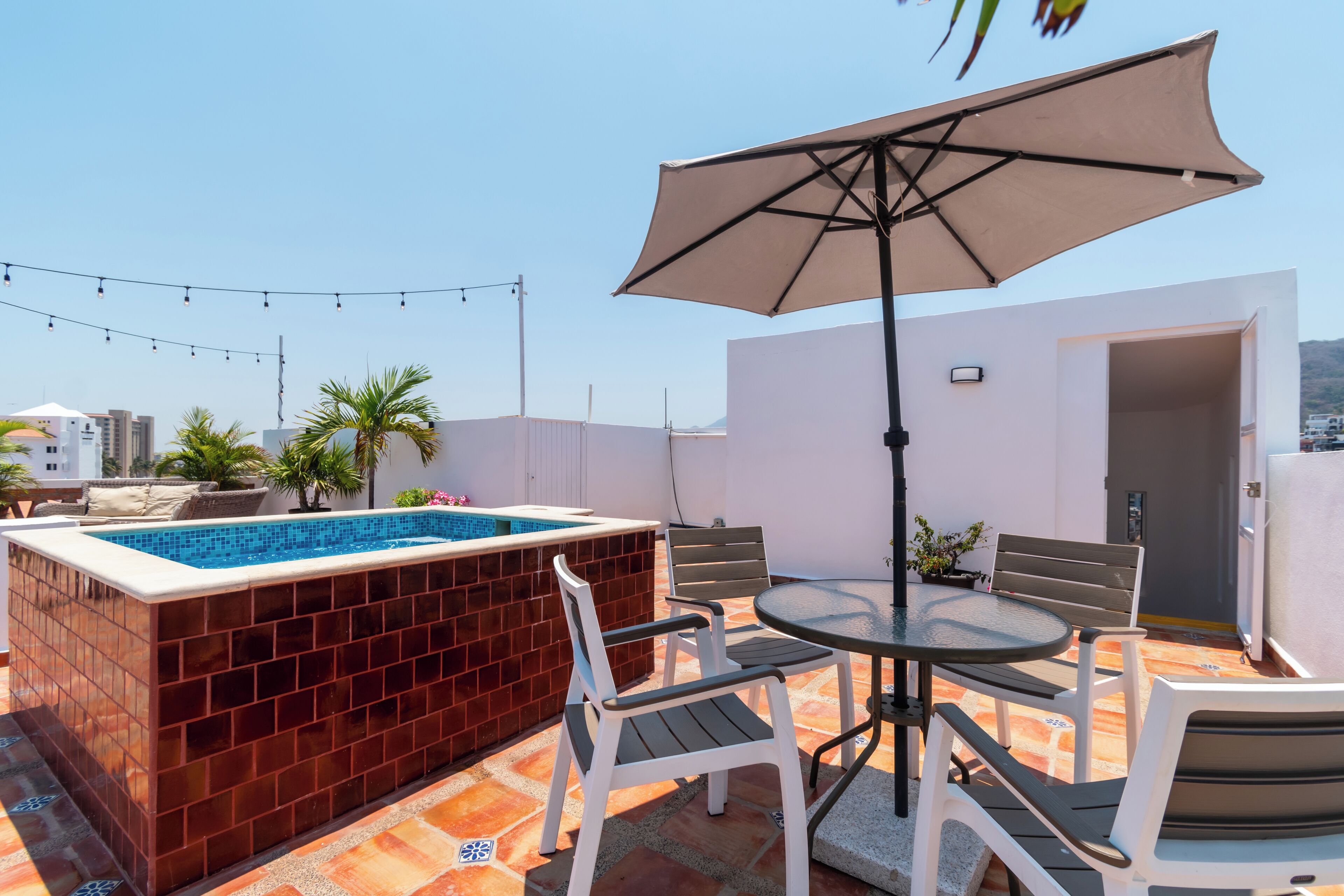 A rooftop terrace with a hot tub, outdoor seating, and a view of the city.