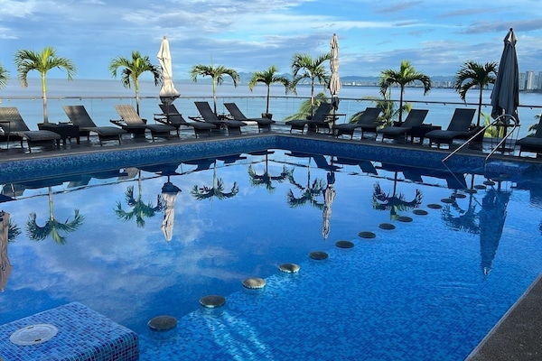 Een buitenzwembad, parasols bij het zwembad en ligstoelen