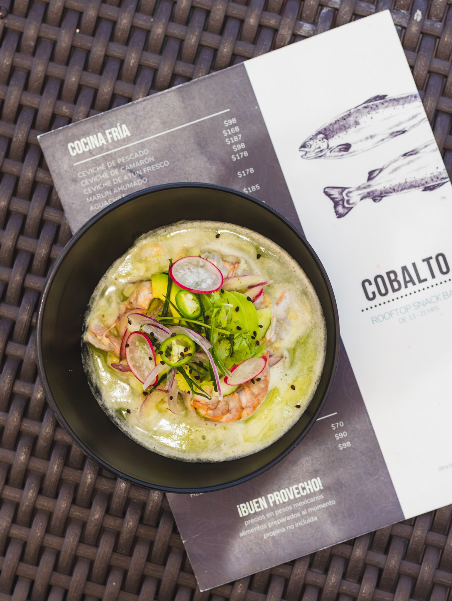 A bowl of seafood soup with shrimp, radishes, and greens, accompanied by a menu listing various dishes and prices.