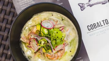 A bowl of seafood soup with shrimp, radishes, and greens, accompanied by a menu listing various dishes and prices.