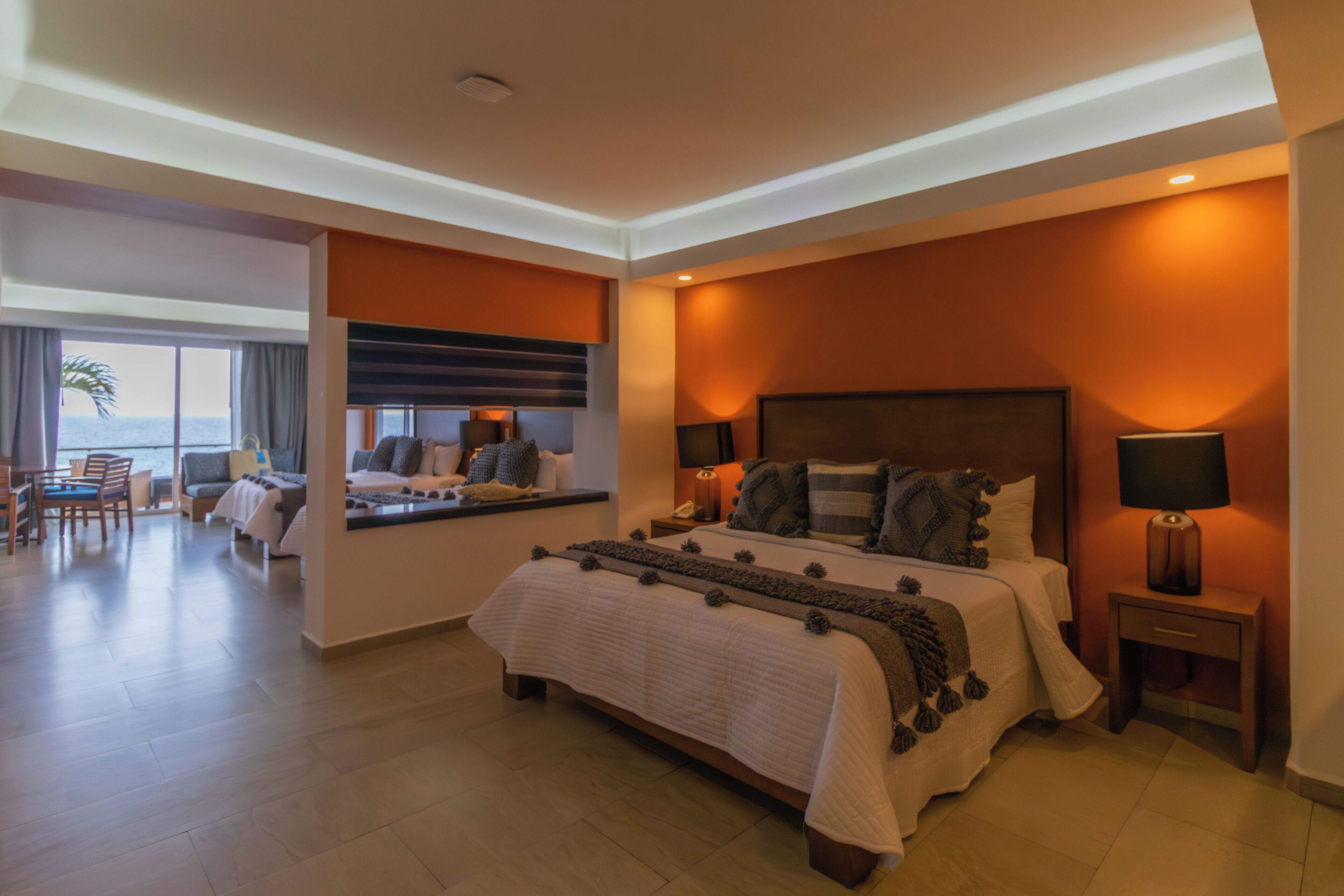 Een moderne hotelkamer met een groot bed, een bureau en uitzicht op de oceaan.