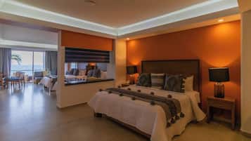 A modern hotel room with a large bed, a desk, and a view of the ocean.