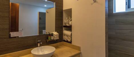A modern bathroom with a large mirror, a beige sink, and a towel rack.