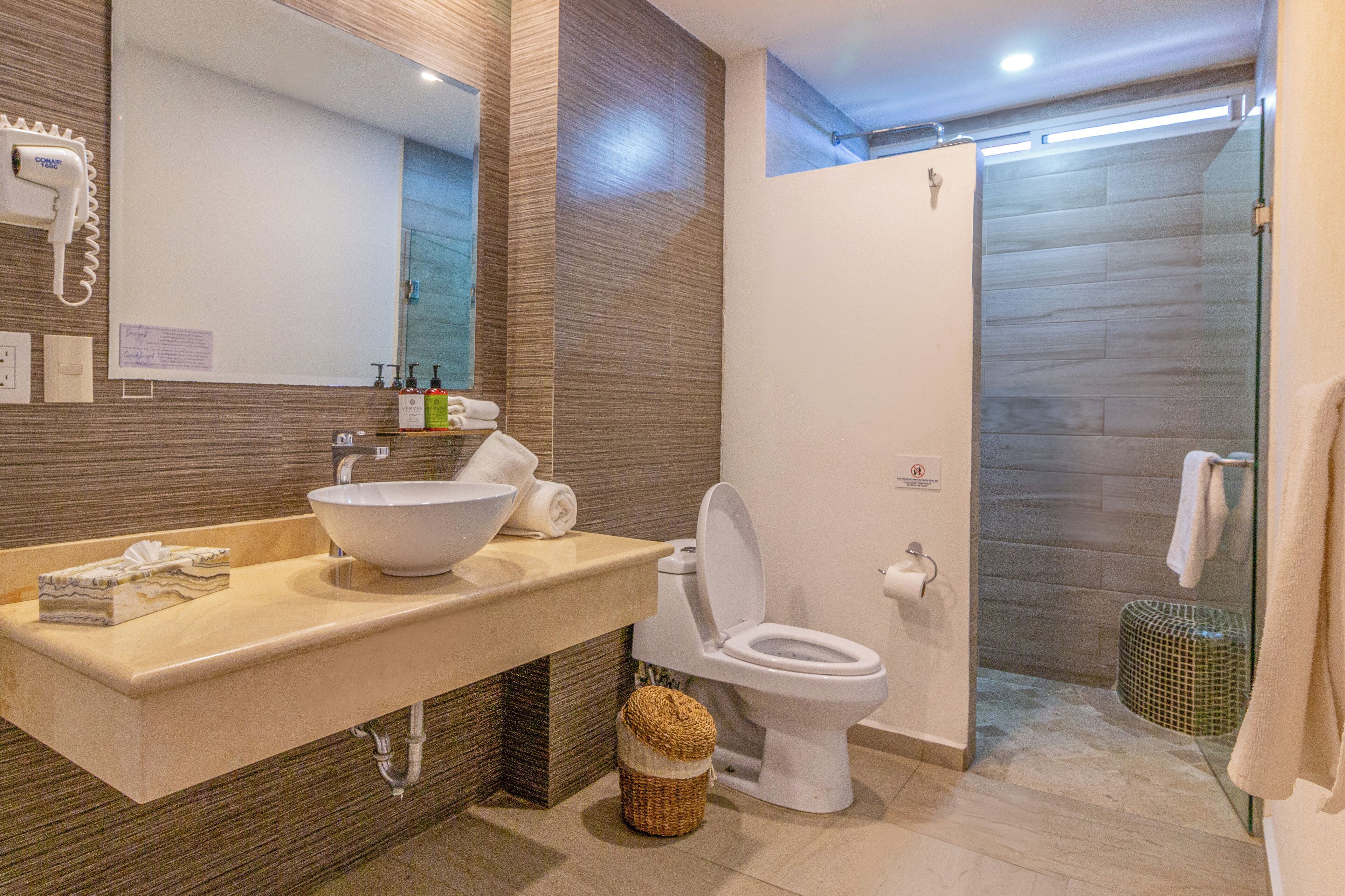 Un baño moderno con un lavamanos grande, inodoro y cabina de ducha de vidrio.