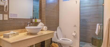 Un baño moderno con un lavamanos grande, inodoro y cabina de ducha de vidrio.