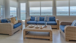A spacious living room with wicker furniture, large windows, and a view of the sea. - The Paramar Beachfront Boutique Hotel - Downtown Malecon (Puerto Vallarta)