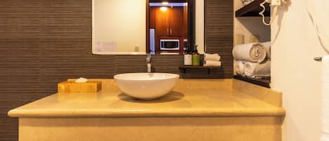 Une salle de bain avec un grand lavabo, un miroir, un sèche-cheveux et des serviettes.