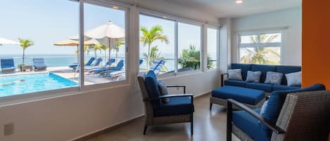 A modern living room with a view of a swimming pool and the ocean.
