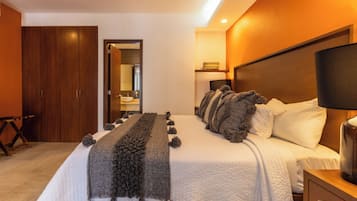 A hotel room with a large bed, a wooden wardrobe, a bedside table with a lamp, and a mirror above the bed.