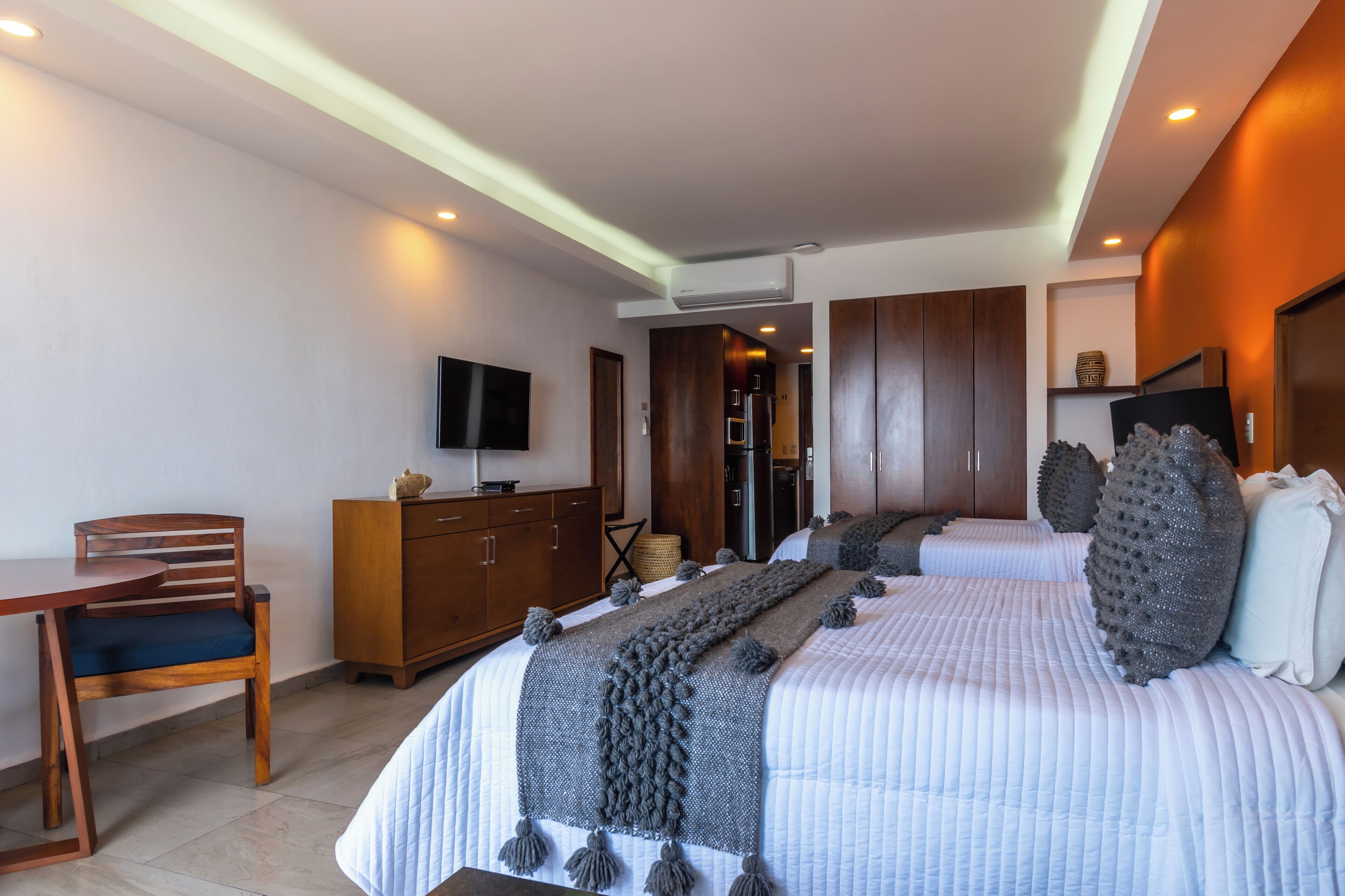 A modern hotel room with a large bed, a desk, a wardrobe, and a television.