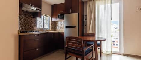 Una cocina moderna con armarios de madera oscura, un refrigerador de acero inoxidable y un comedor con mesa y sillas de madera.
