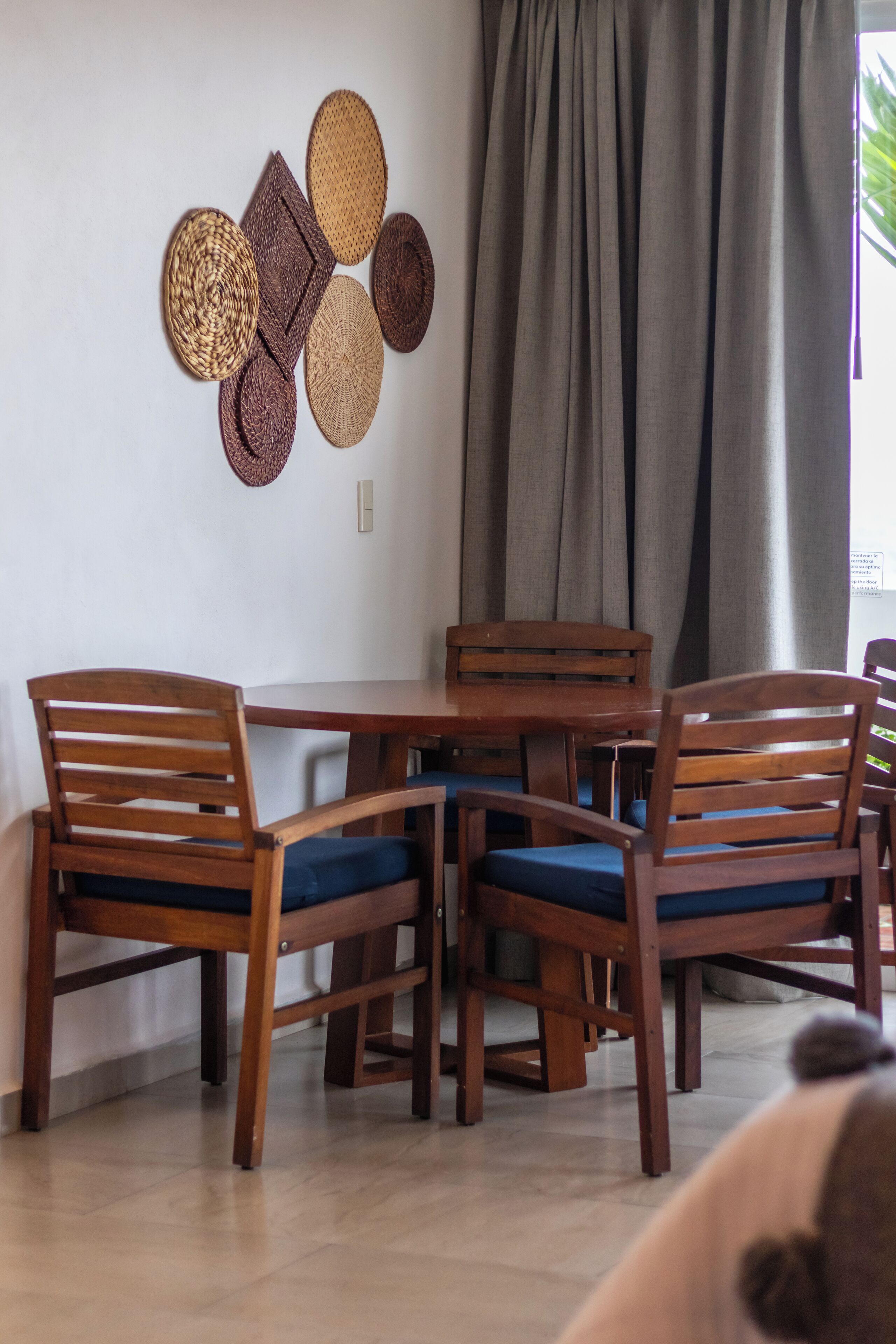 Un comedor con una mesa redonda de madera y cuatro sillas con cojines azules.