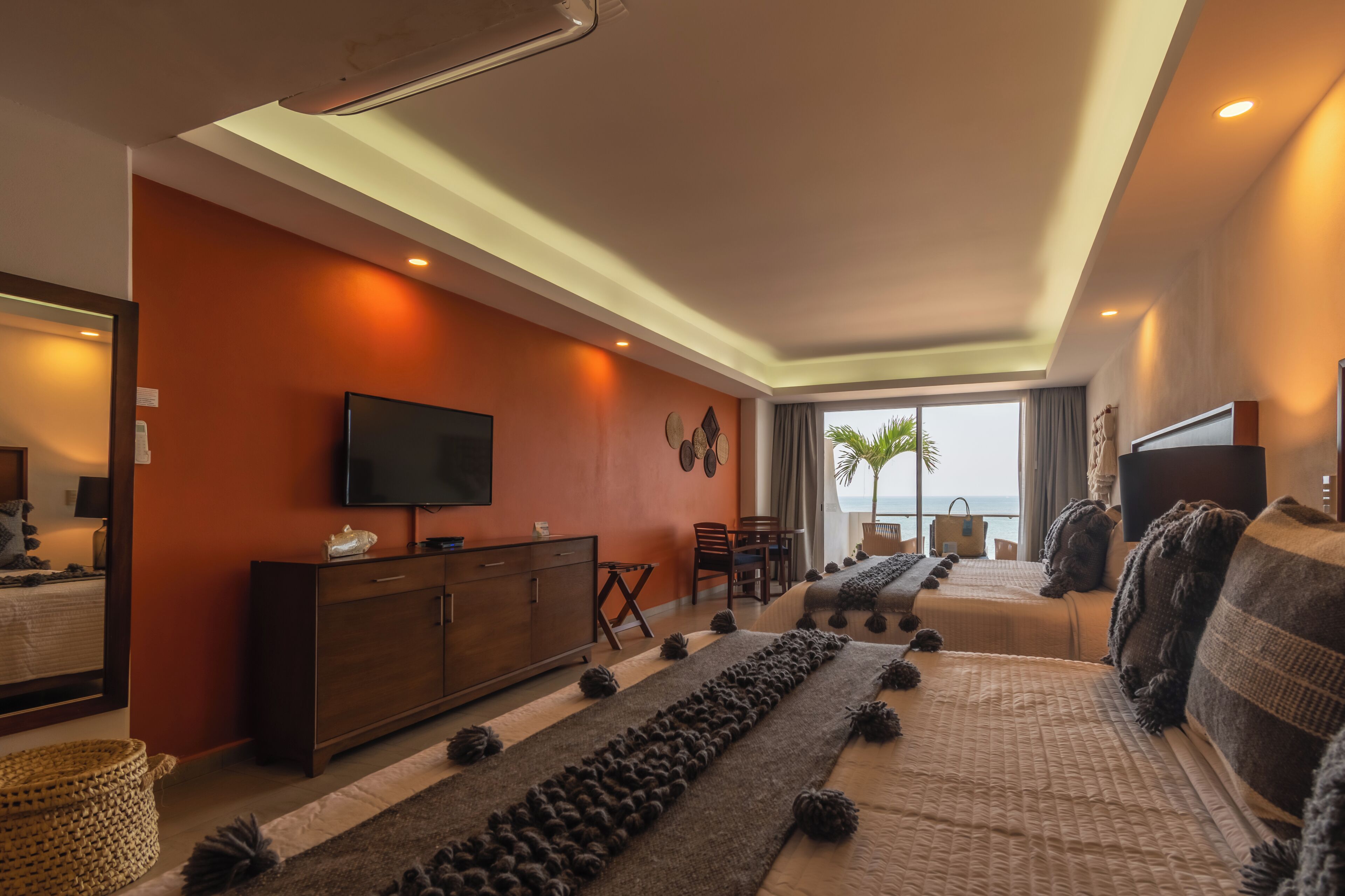 Una habitación de hotel moderna con una cama grande, televisión, escritorio y vista al océano.