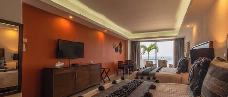 Una habitación de hotel moderna con una cama grande, televisión, escritorio y vista al océano.