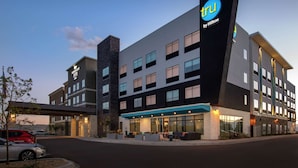 Un hôtel moderne, reconnaissable à son enseigne « tru by Hilton » bien visible, avec de nombreux étages et un hall d’entrée bien éclairé.