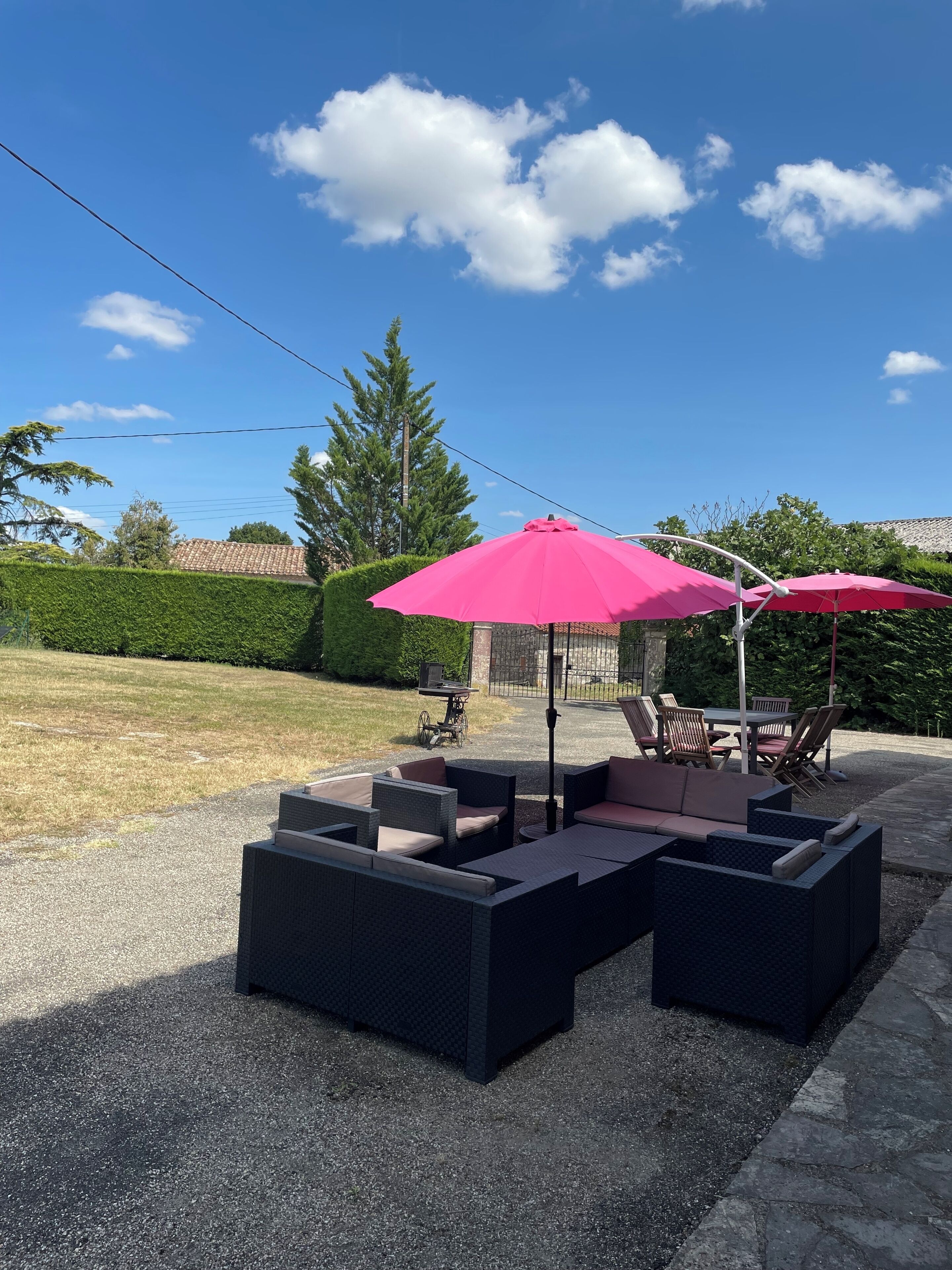 An outdoor patio area with black cushioned seating and two pink umbrellas.