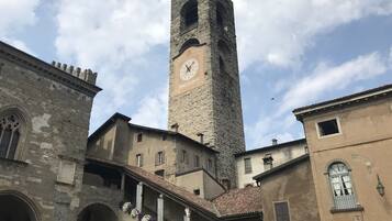 A historic building with a prominent clock tower, arched windows, and a staircase leading to an upper level.