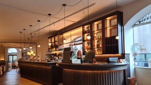 A bar area with wooden bar counters, hanging pendant lights, and shelves stocked with bottles. - Il Sole Bergamo (Bergamo)