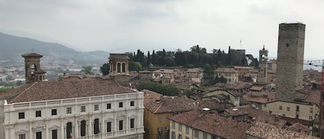 A historic square with a prominent building featuring a central courtyard and a bell tower.