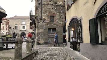 Eine Kopfsteinpflasterstraße mit historischen Gebäuden, einer Steinfontäne und einem Restaurant namens "Ristorante Sole".