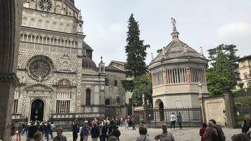 A historic building with intricate architecture, including domes and columns, surrounded by a cobblestone courtyard.