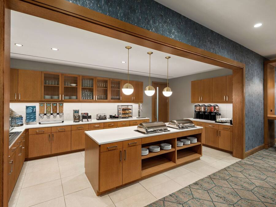 A modern kitchen with wooden cabinets, a central island, and pendant lighting.
