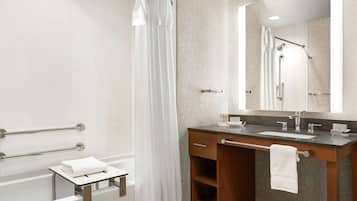 A modern bathroom with a bathtub, a shower, a vanity with a sink, and a large mirror.