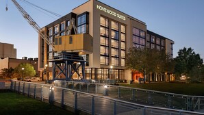 A modern building with "HOMEWOOD SUITES" signage, featuring a prominent entrance with glass doors, a visible elevator, and a construction crane nearby. - Homewood Suites by Hilton Wilmington Downtown (Wilmington)