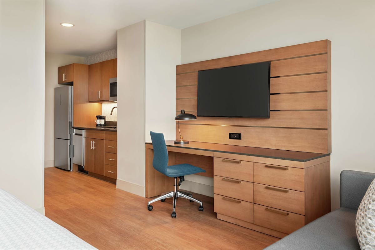 A modern kitchen with wooden cabinets, a built-in microwave, and a stainless steel refrigerator.