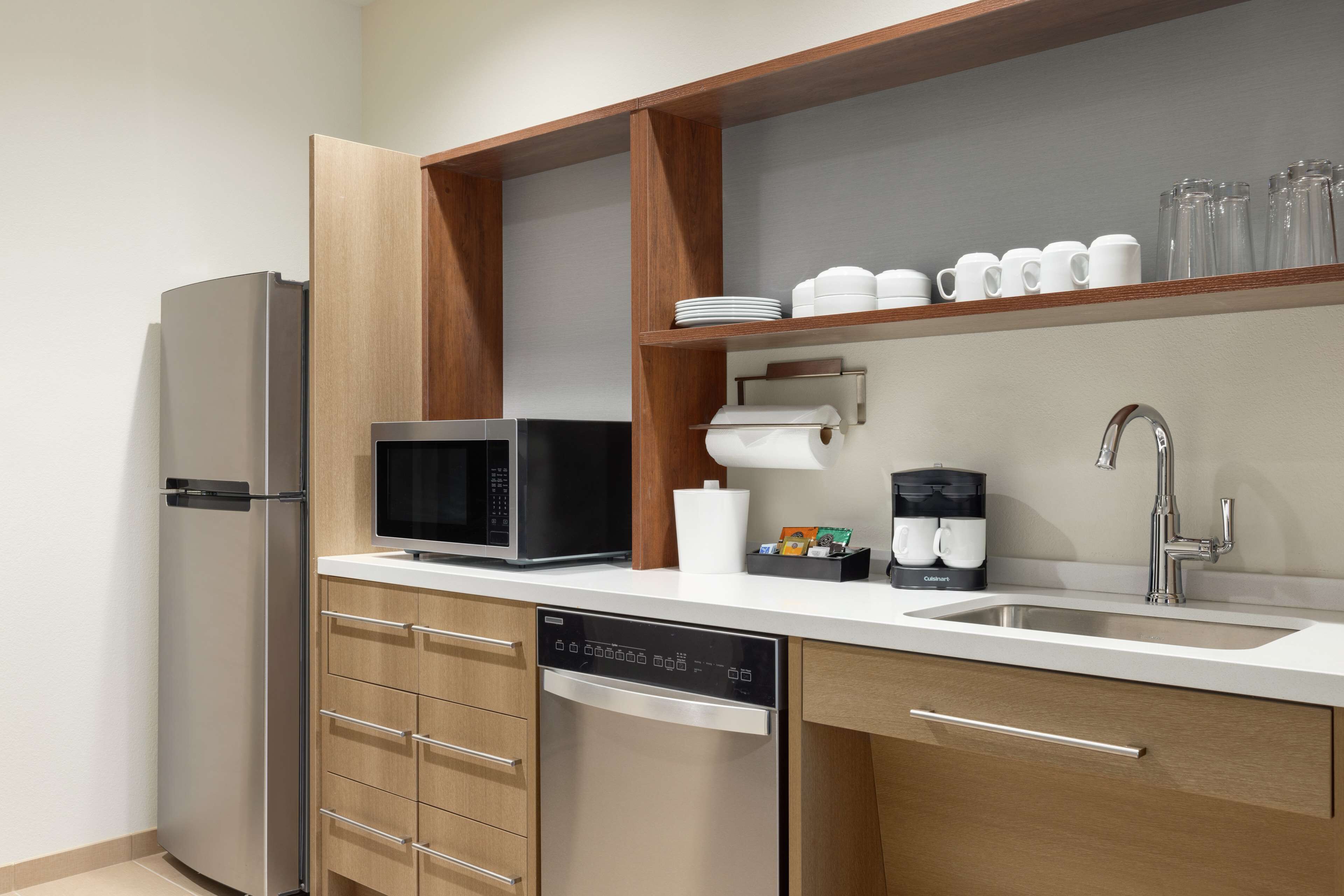 A modern kitchen with a built-in dishwasher, a microwave, a coffee maker, and a stainless steel sink.